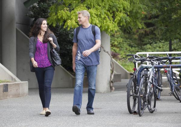 a male and female student walk side-by-side through campus